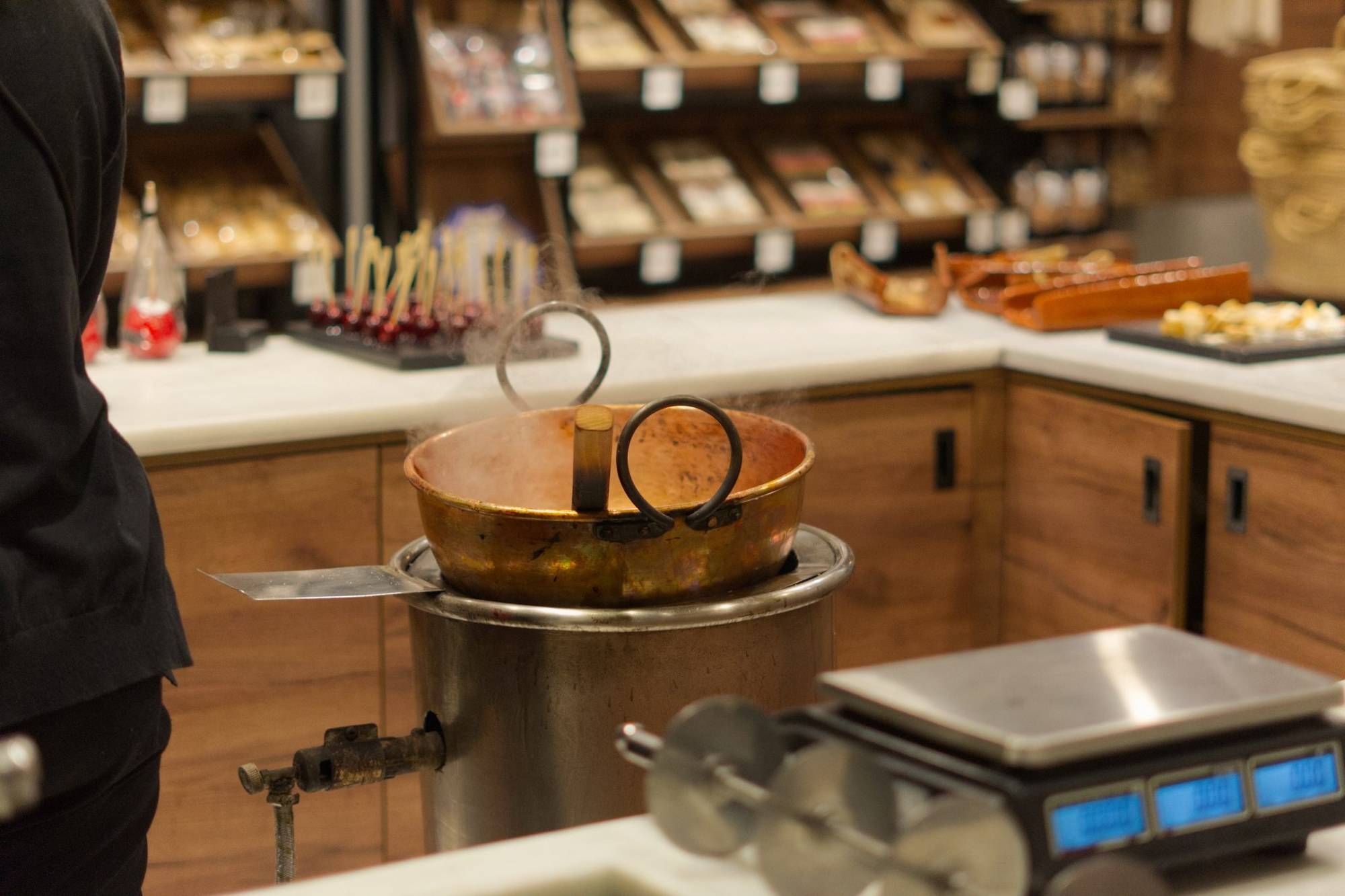Comptoir d’une boutique indépendante : chaudron en cuivre, balance et étagères de produits en bois